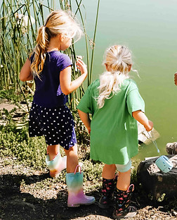 Forest school educator guiding children in nature-based learning by a pond during outdoor education.