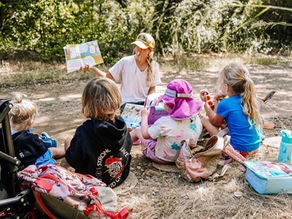 Children sitting together during snack time and listening to a story at Buena Vista Park in Vista, building community and early literacy skills at a nature school.